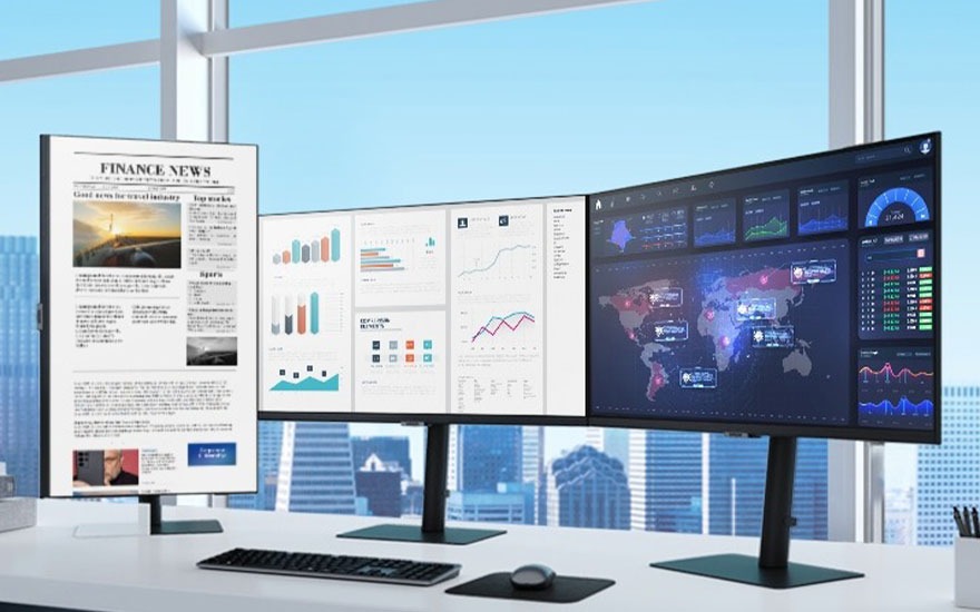 Wide monitor shows data, charts and world map beside a vertical screen with financial news in a modern office.