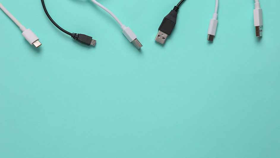 Vijf USB-kabels, zwart en wit, liggen op een blauwgroene achtergrond. De kabels hebben verschillende aansluitingen.