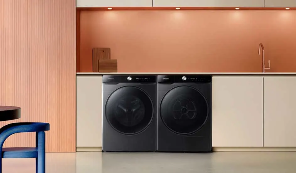 Stijlvolle keuken met zachte perzikkleurige achterwand, witte kasten en twee grote zwarte wasmachines of drogers strak naast elkaar.