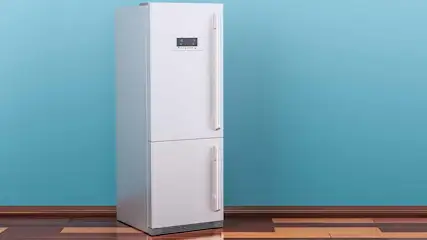 Witte koelkast met display tegen een blauwe muur op een houten vloer. De koelkast heeft twee deuren met handgrepen.