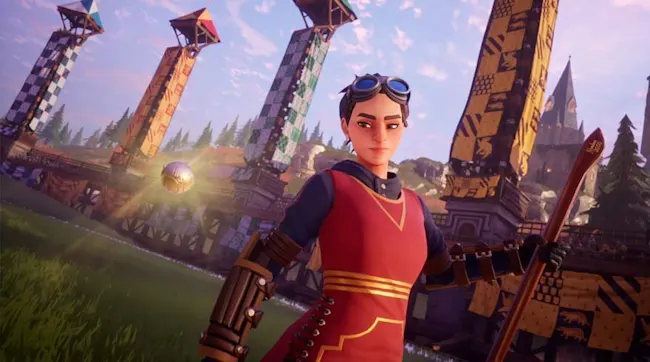 Een persoon met een bril draagt een rood vest met goudkleurige accenten. Op de achtergrond staan torens en een gouden bal.