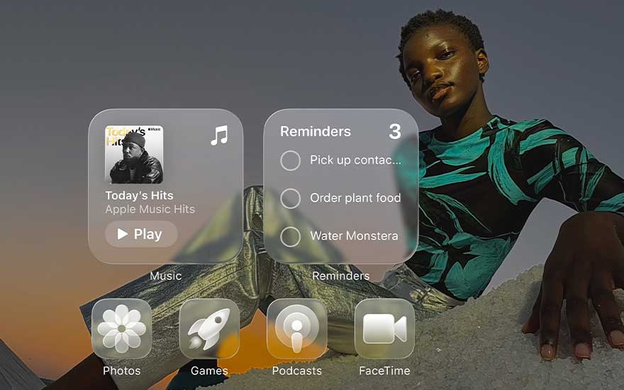 A person poses at sunset behind large floating iPhone widgets for music, reminders, photos, games, podcasts and FaceTime.