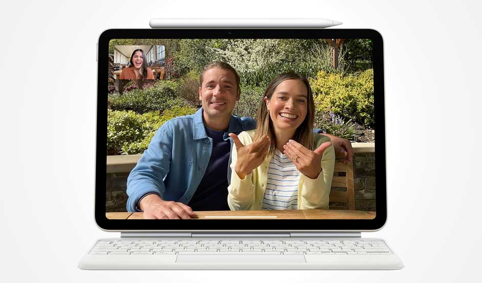 On a tablet screen, a couple on a video call outdoors proudly shows their rings to a smiling friend in the small corner window.