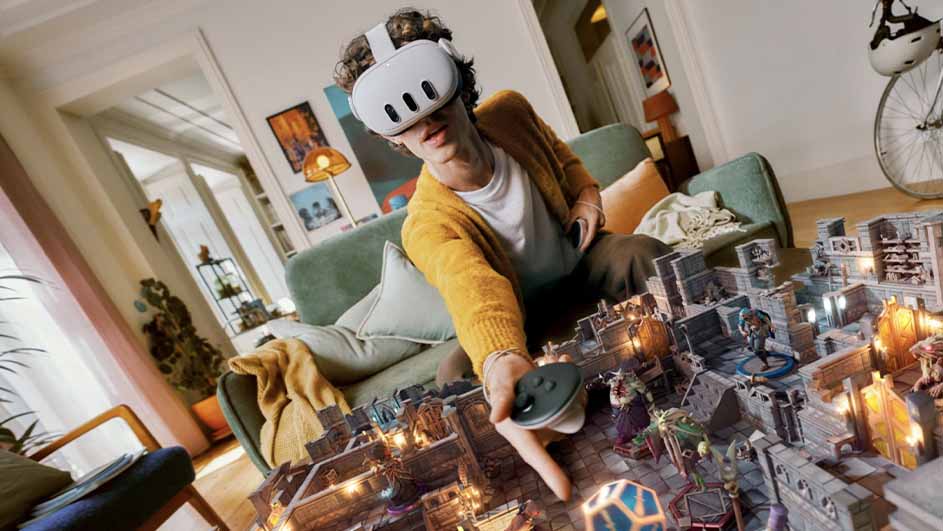 Een persoon met een VR-bril zit op een groene bank en speelt een virtueel strategiespel met miniaturen.