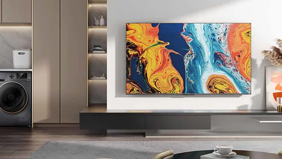 Wasmachine naast kast met open schappen. Tv met abstract kunstwerk erboven. Zwarte tv-meubel. Koffiekopje op salontafel.