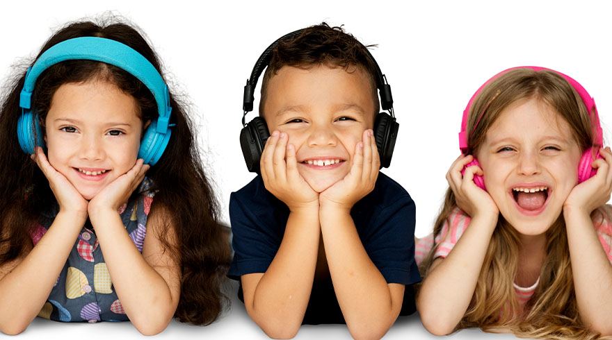 Drie lachende kinderen met een blauwe, zwarte en roze hoofdtelefoon liggen op een witte achtergrond, steunend op hun handen.