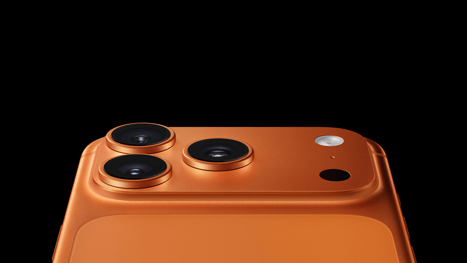 Oranje smartphone met drie grote cameralenzen en flitser steekt minimalistisch uit een zwarte achtergrond.