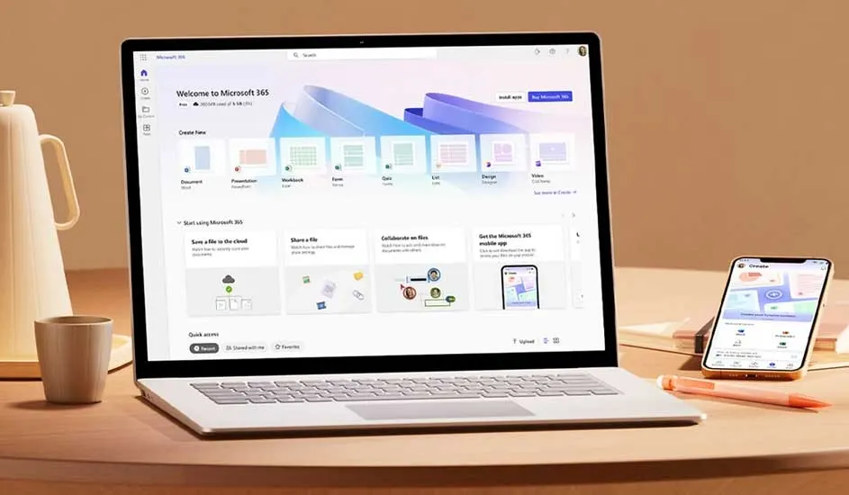 Open laptop showing Microsoft 365 home screen, with smartphone, mug and pen on a round table in warm soft lighting.