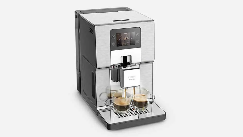 Een zilverkleurig koffiezetapparaat vult twee glazen kopjes met donkere koffie op een zwart rooster.