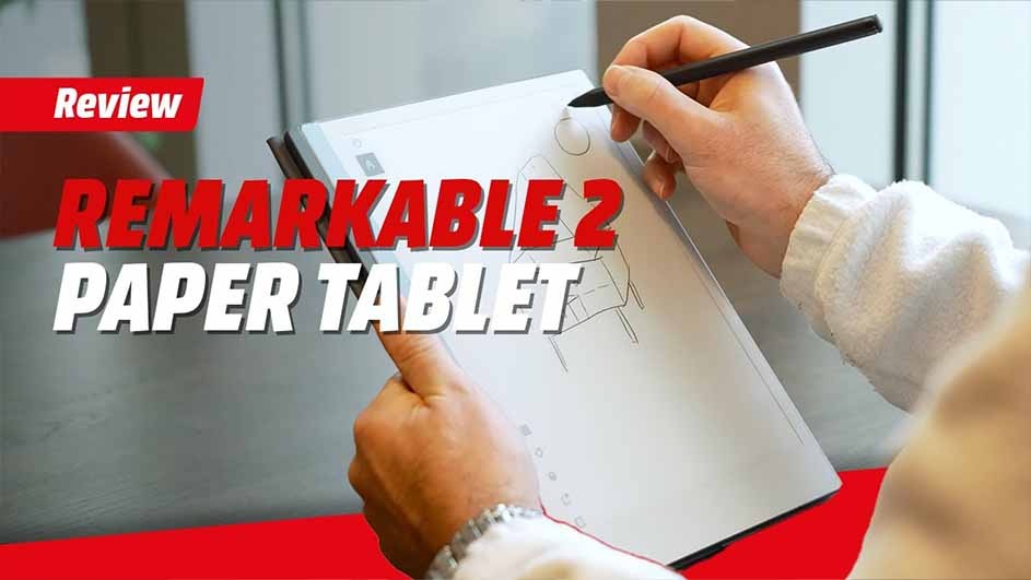 Hands hold a Remarkable 2 paper tablet and a black stylus, drawing on the screen. Review text appears in red and white.