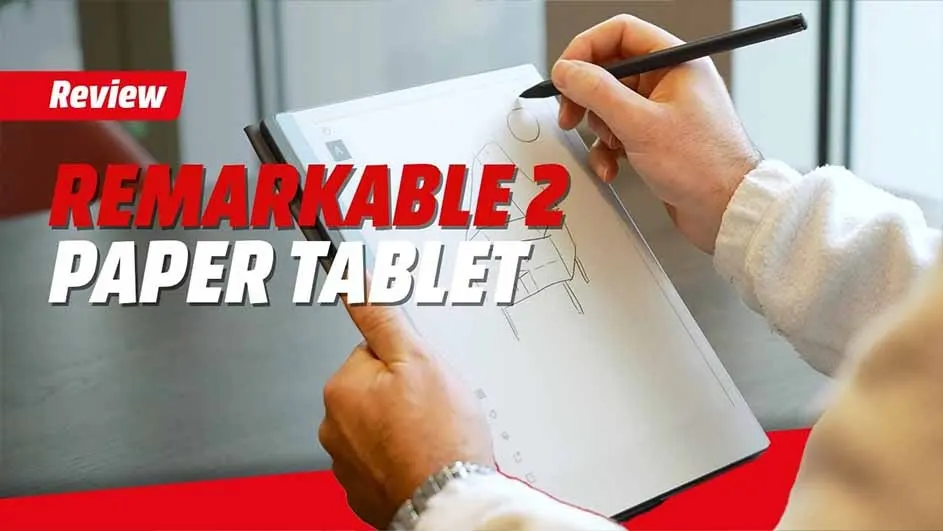 Hands hold a Remarkable 2 paper tablet and a black stylus, drawing on the screen. Review text appears in red and white.