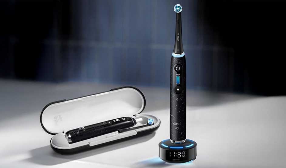 Moderne elektrische tandenborstels met verlichte ringen en standen, gekoppeld aan een smartphone-app die zes poetszones toont.