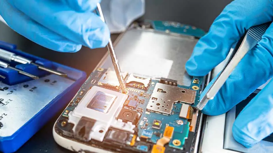 Handen met blauwe handschoenen repareren een telefoon met een schroevendraaier en pincet. Er ligt een blauwe gereedschapskist naast.