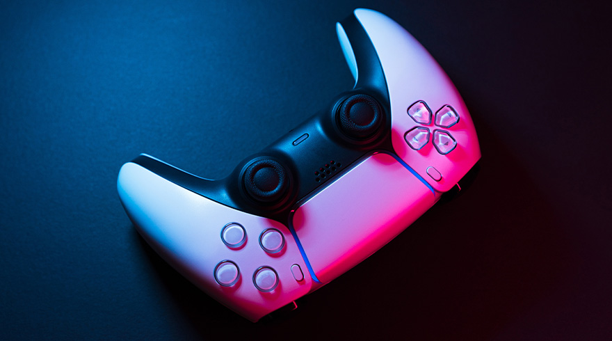 Een witte PlayStation 5-controller ligt op een donkere achtergrond, belicht met roze en blauwe accenten.
