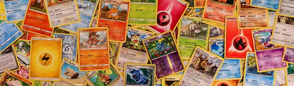 Een verzameling Pokémon-kaarten in diverse kleuren, waaronder blauw, groen, oranje, geel en paars, verspreid over een vlakke ondergrond.