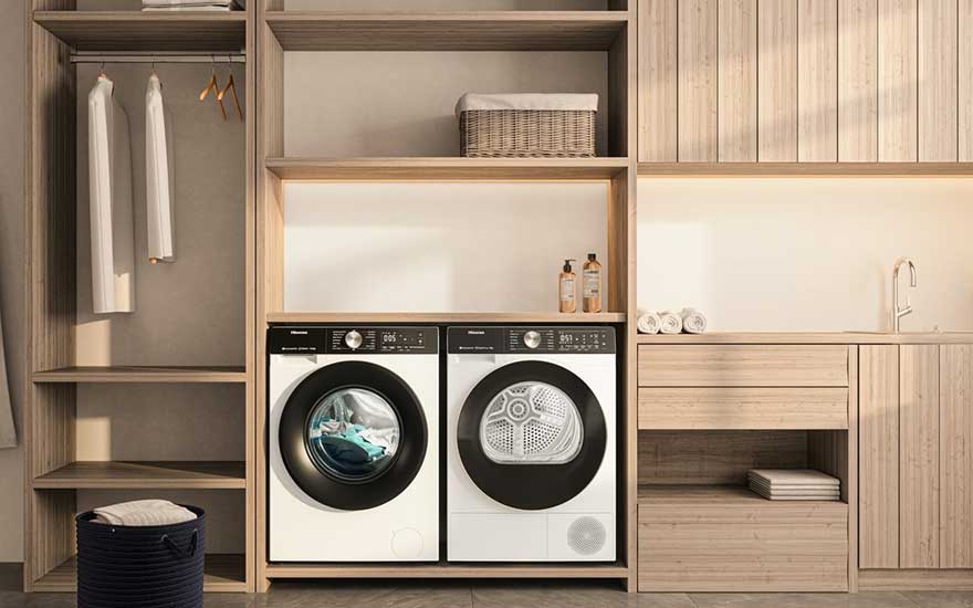 Een moderne witte wasmachine en droger in een houten nis, mooie opbergmanden, verzorgingsproducten en opgevouwen was binnen handbereik.