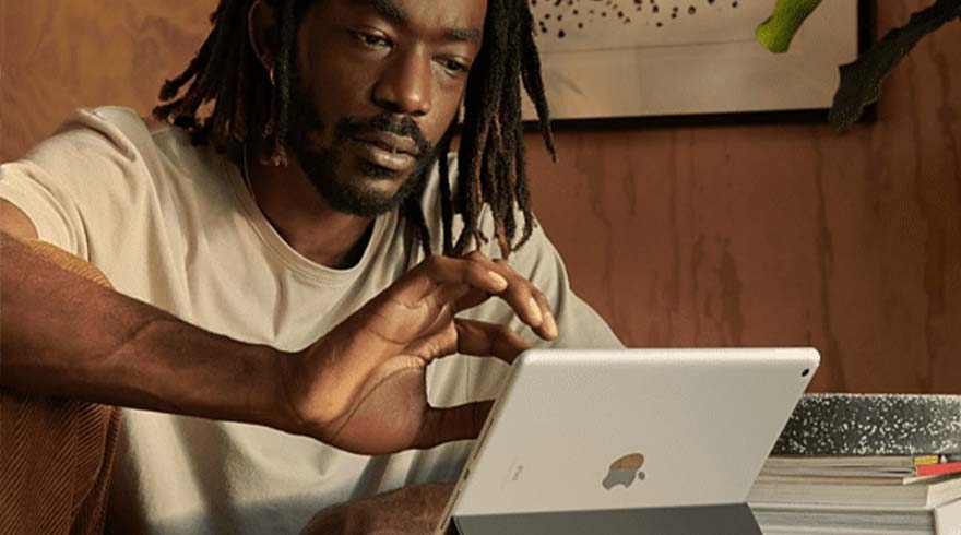 Man gebruikt een tablet in een kamer met houten panelen. Op de achtergrond staat kunst en boeken.