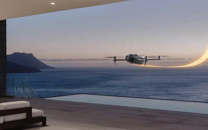 Een drone vliegt boven een zwembad met uitzicht op zee bij zonsondergang, met een lichtspoor in de lucht langs het water.