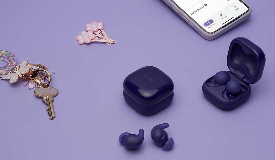 Op een paarse ondergrond liggen paarse Sony draadloze oordopjes met oplaadcase, een sleutelbos, haarspeldjes en een smartphone.