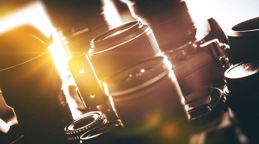 Een close-up van meerdere camera lenzen in verschillende maten, met een zachte lichtbron die van links schijnt.