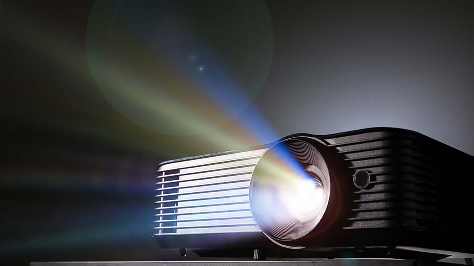 Een projector straalt licht uit in een donkere omgeving. De projector is zwart met witte details.