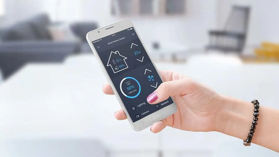 Een hand houdt een smartphone vast met een app voor huisautomatisering, met op de achtergrond een vage woonkamer.