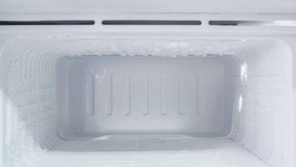 Een lege, witte vriezer is bedekt met ijs aan de binnenkant.
