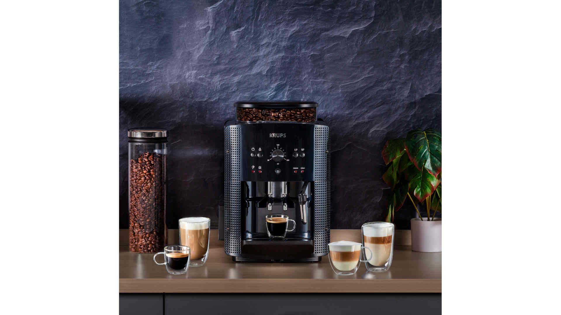 Een koffiezetapparaat met koffiebonen, een pot bonen en diverse koffiedranken op een aanrecht.