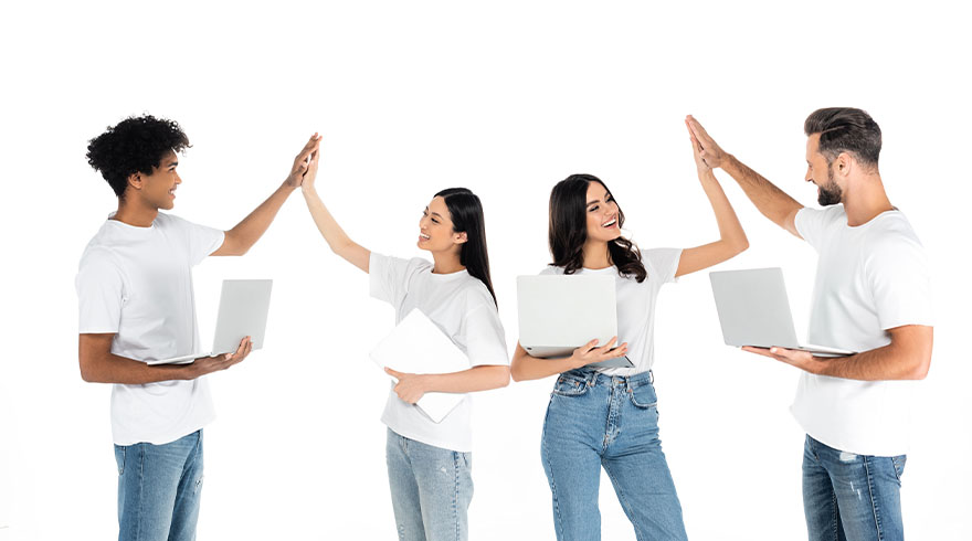 Vier mensen in witte shirts en blauwe jeans geven elkaar een high-five, met laptops in hun handen op een witte achtergrond.