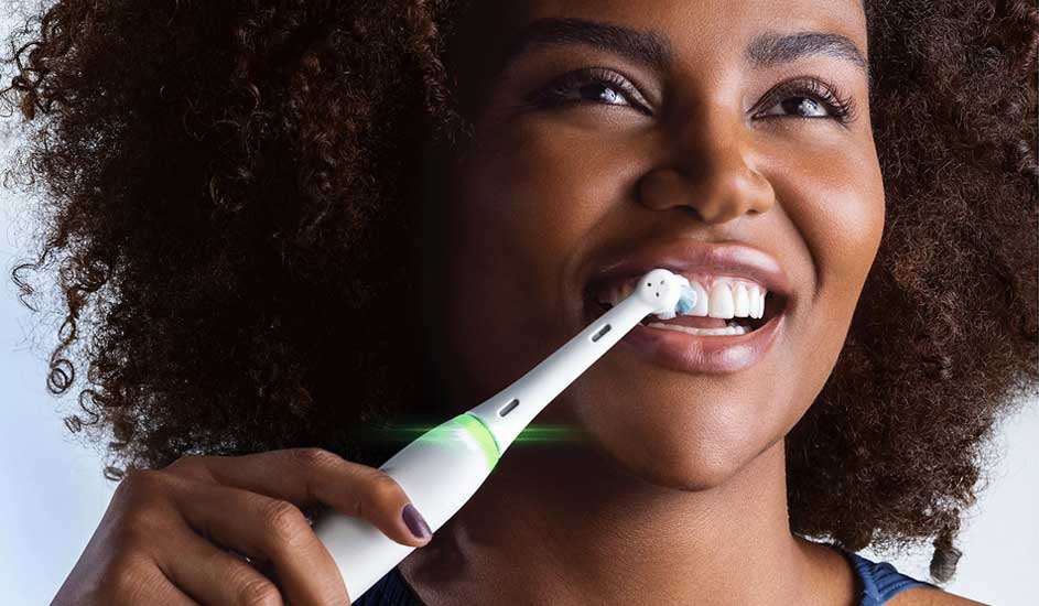 Een hand houdt een wit scheerapparaat van het merk Philips tegen de hals, met donkere krullende haren op de achtergrond zichtbaar.