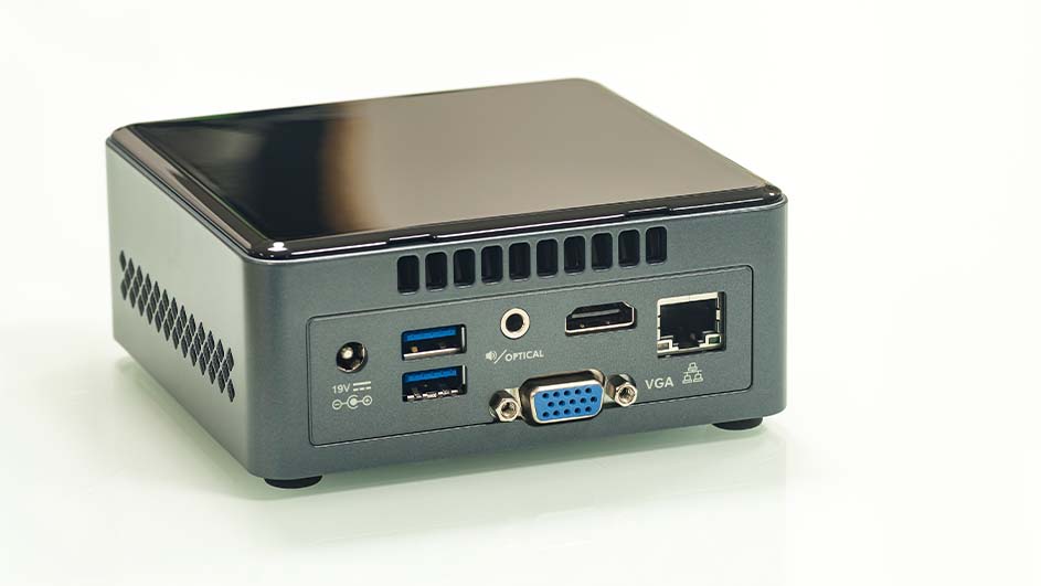 Kleine grijze computer met zwarte bovenkant, met poorten voor USB, HDMI, VGA en Ethernet aan de achterkant.