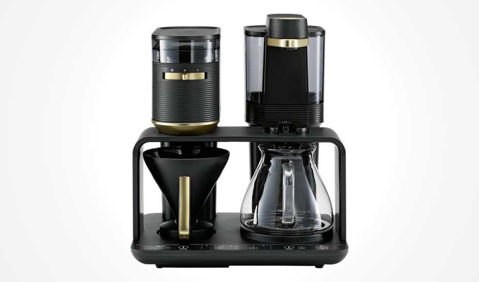 Een zwarte filterkoffiemachine met goudkleurige accenten toont een kan, filterhouder, waterreservoir en bedieningsknoppen vooraan.