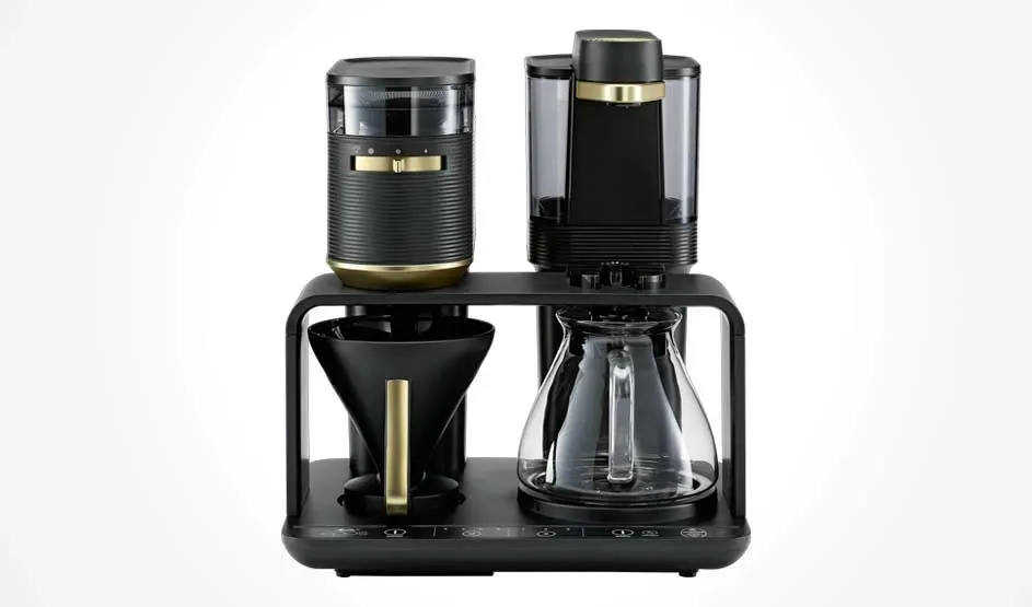 Een zwarte filterkoffiemachine met goudkleurige accenten toont een kan, filterhouder, waterreservoir en bedieningsknoppen vooraan.