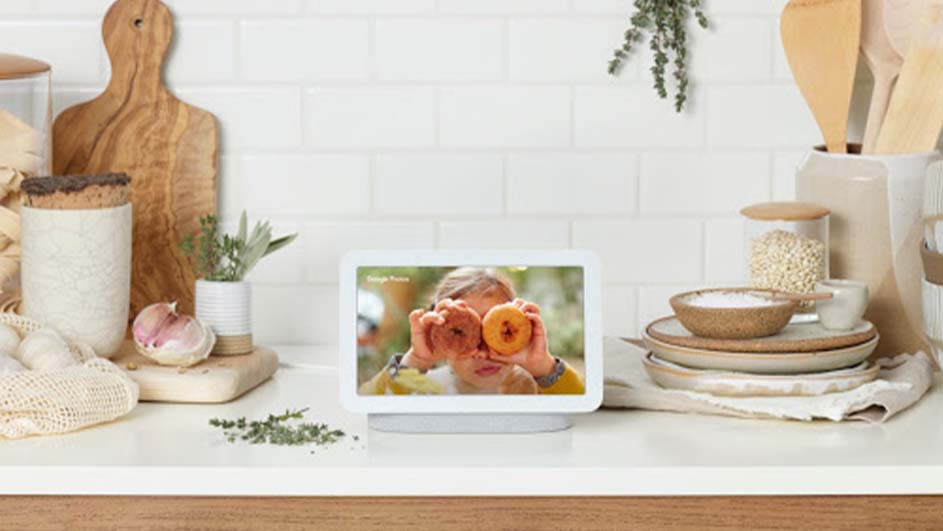 Keukenopstelling met houten snijplank, potten, schalen en een witte smarthub die een kind met donuts voor de ogen toont.