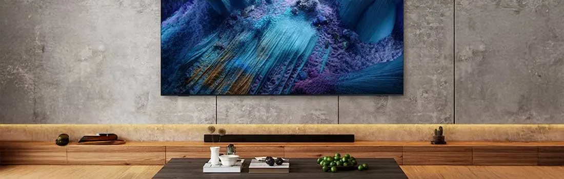 Luxe woonkamer met grote Samsung TV aan betonnen muur, houten mediameubel en moderne salontafel met decoratieve items.