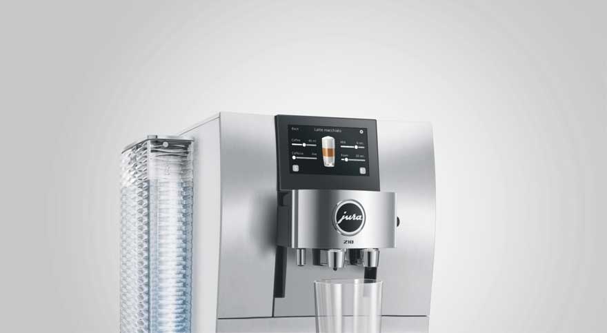Een moderne zilverkleurige Jura Z10 koffiemachine met touchscreen, zichtbaar waterreservoir en een glas onder de uitloop.