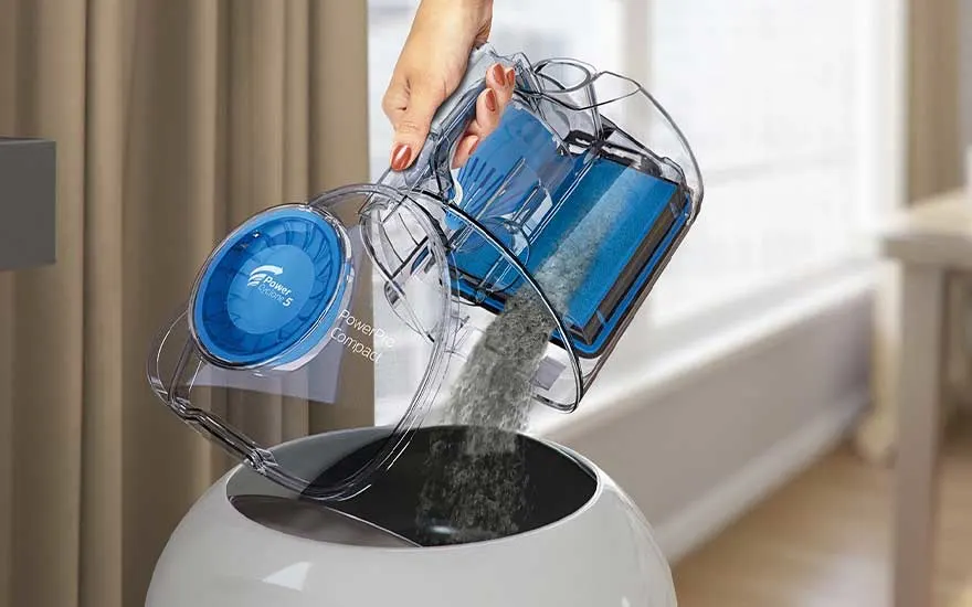 Een stofcontainer wordt eenvoudig geleegd boven een prullenbak, hygiënisch en zonder stofwolken.