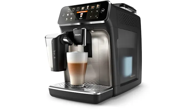 Zwart Philips koffiezetapparaat met melkreservoir en een glas gelaagde koffie op een roestvrijstalen lekbak.