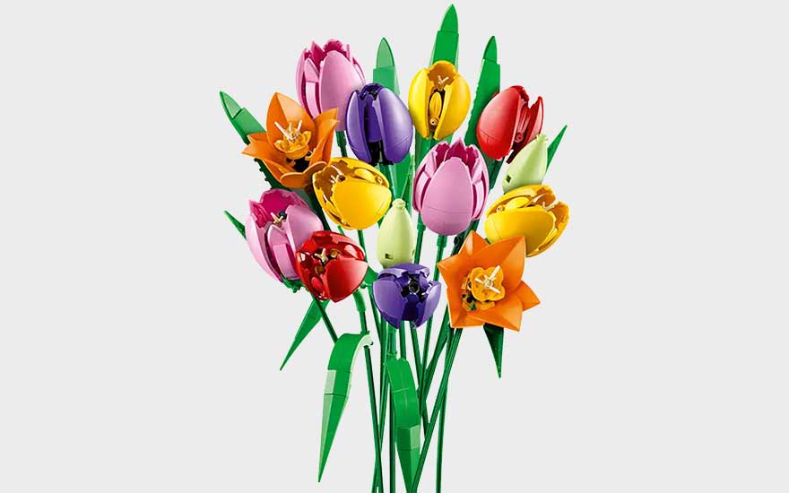 Kleurrijk LEGO-boeket met tulpen en narcissen in rood, geel, paars, roze en oranje, op groene stelen met bladeren.