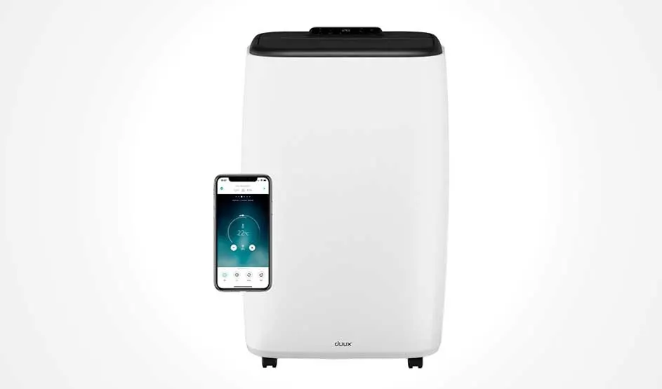 A white Duux portable air conditioner with a black top is shown, next to a smartphone displaying its control app, against a plain background.