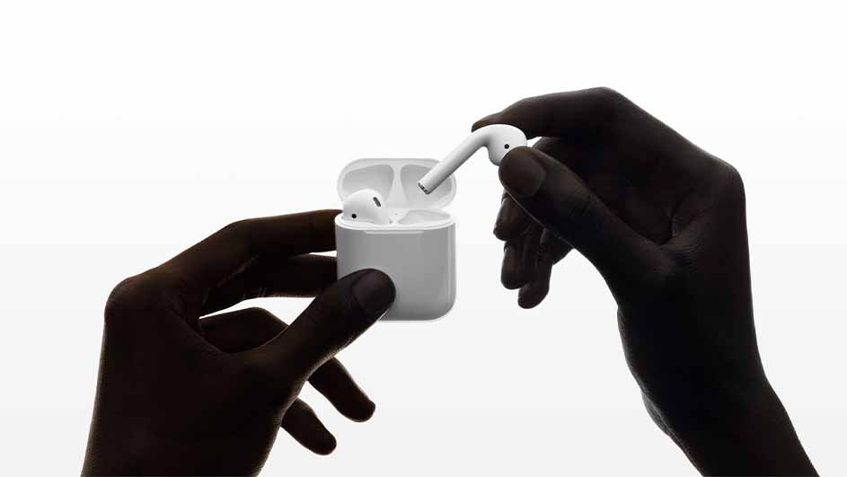 Two hands hold a white case with white wireless earbuds against a white background, one earbud is held separately.