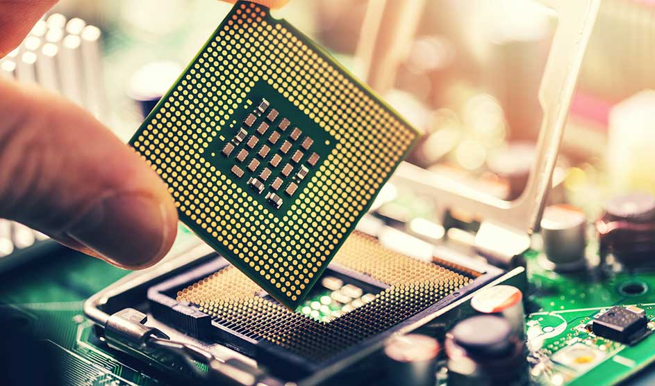 Een hand plaatst een processor van Intel op een moederbord. Je ziet duidelijk de pinnen en het technische binnenwerk van de computer.