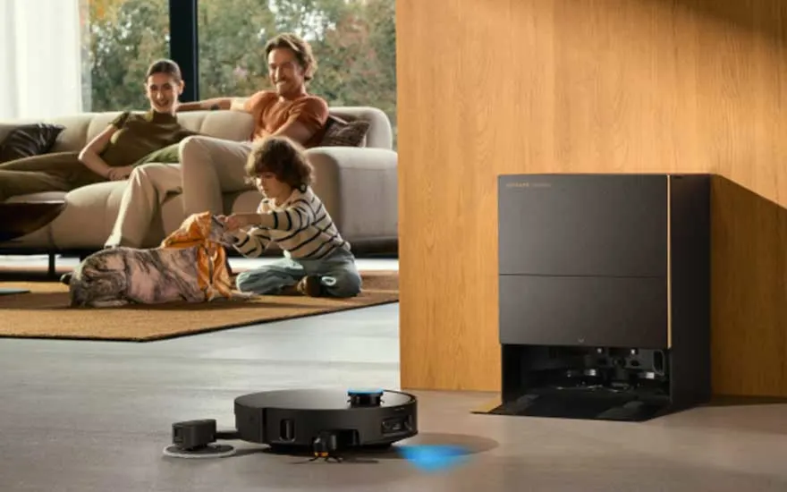 Een gezin ontspant met een hond in de woonkamer terwijl een robotstofzuiger bij zijn grote station de vloer reinigt.