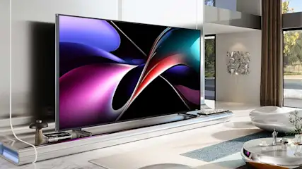 Een moderne televisie toont levendige abstracte kunstwerken in paars, magenta, cyaan en rood op zwarte achtergrond. Luxe woonkamer met raam, plant, decoratie. Minimalistisch design met uitstekende beeldkwaliteit.