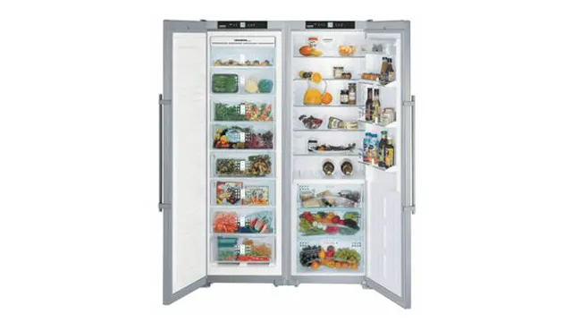 Een openstaande, zilverkleurige koelkast met twee deuren, gevuld met diverse voedingsmiddelen zoals groenten, fruit en drankjes.