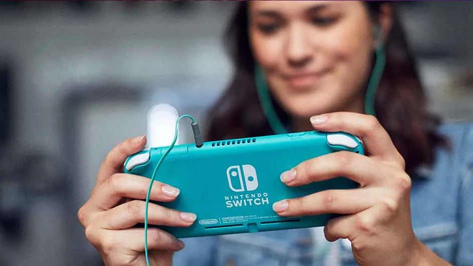Een vrouw houdt een blauwe Nintendo Switch vast met groene oortjes aangesloten.