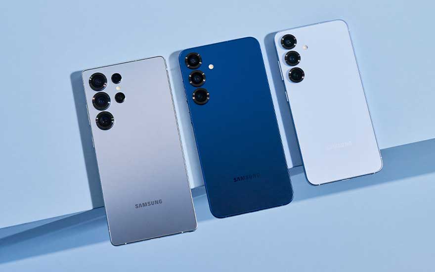 Three Samsung smartphones rest side by side on a light blue set, their backs highlighting multiple camera lenses and sleek colours.