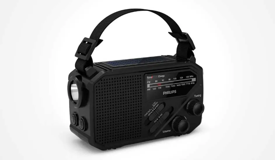Op een witte achtergrond staat een zwarte Philips draagradio met stevige draagriem, grote knoppen en zichtbare tuner en speaker.