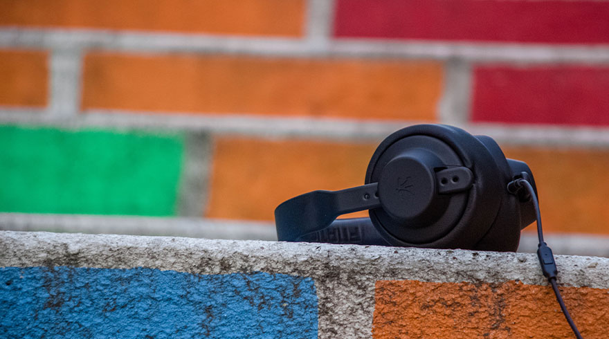 Zwarte hoofdtelefoon ligt op een muur met blauwe, groene, oranje en rode bakstenen.