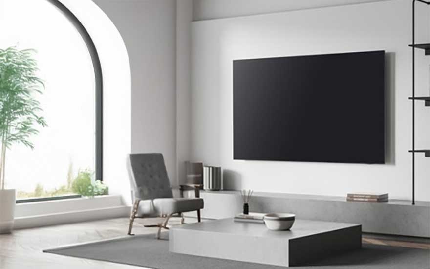 Minimalistische witte woonkamer met zwarte TV aan de muur, moderne fauteuil en groot boogvenster met groene planten.